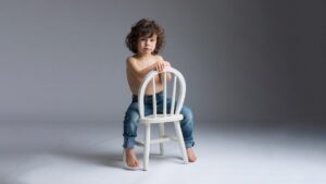 photo studio d'un petit garçon assis sur sa chaise