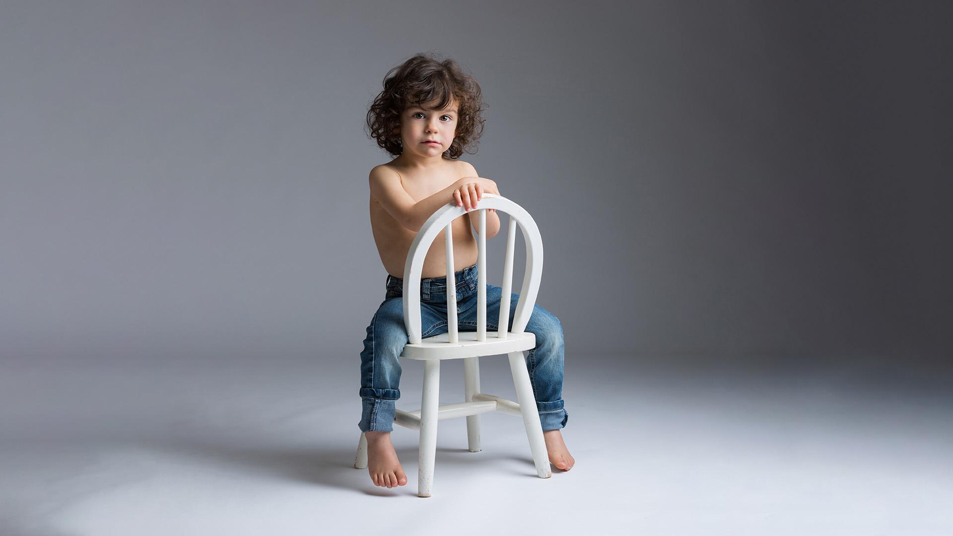 photo studio d'un petit garçon assis sur sa chaise